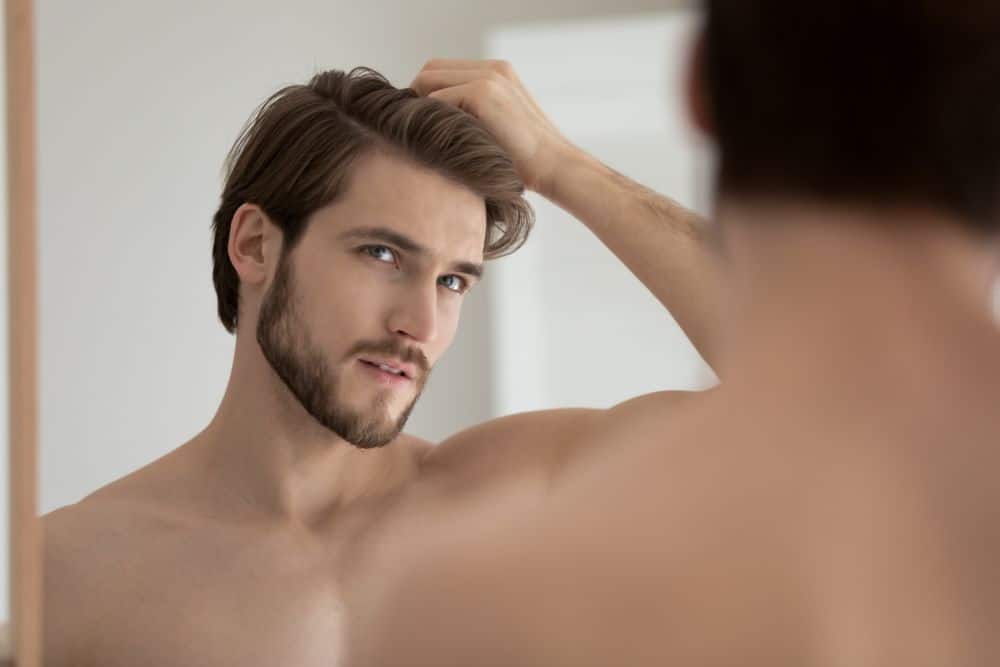 Concerned middle-aged man watching his hair in the mirror.