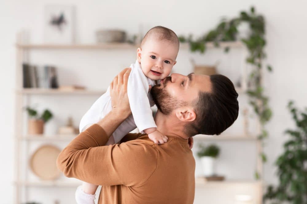 Happy father holding his toddler in arms.