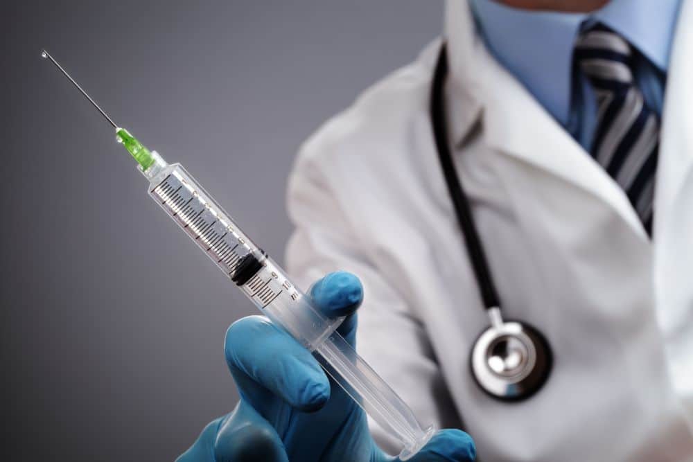 A male urologist holding a syringe with injection for ED treatment