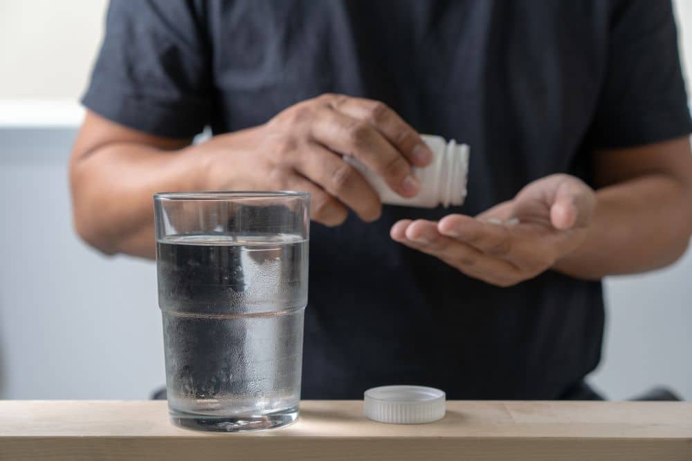 A man taking a magnesium pill out of a bottle.