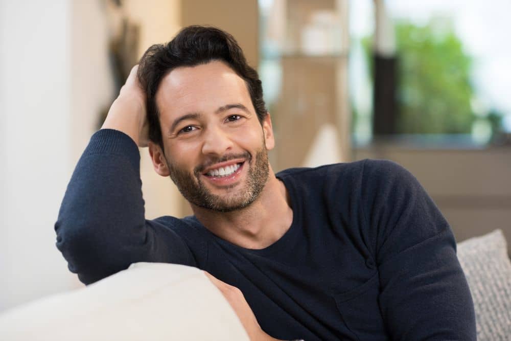 happy smiling middle-aged man sitting comfortably on a sofa