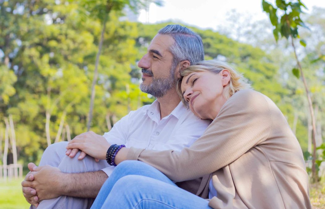 A middle-aged couple sits outdoors