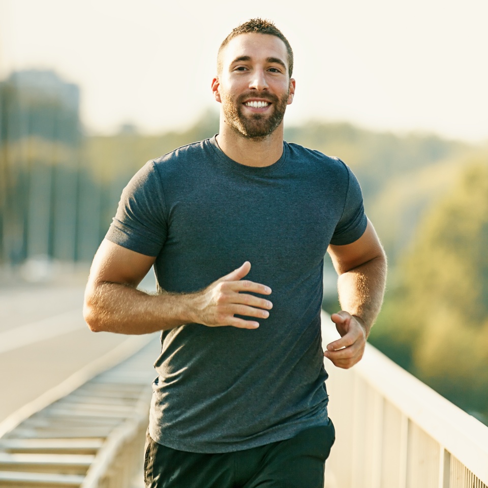 Handsome young man running across the bridge.