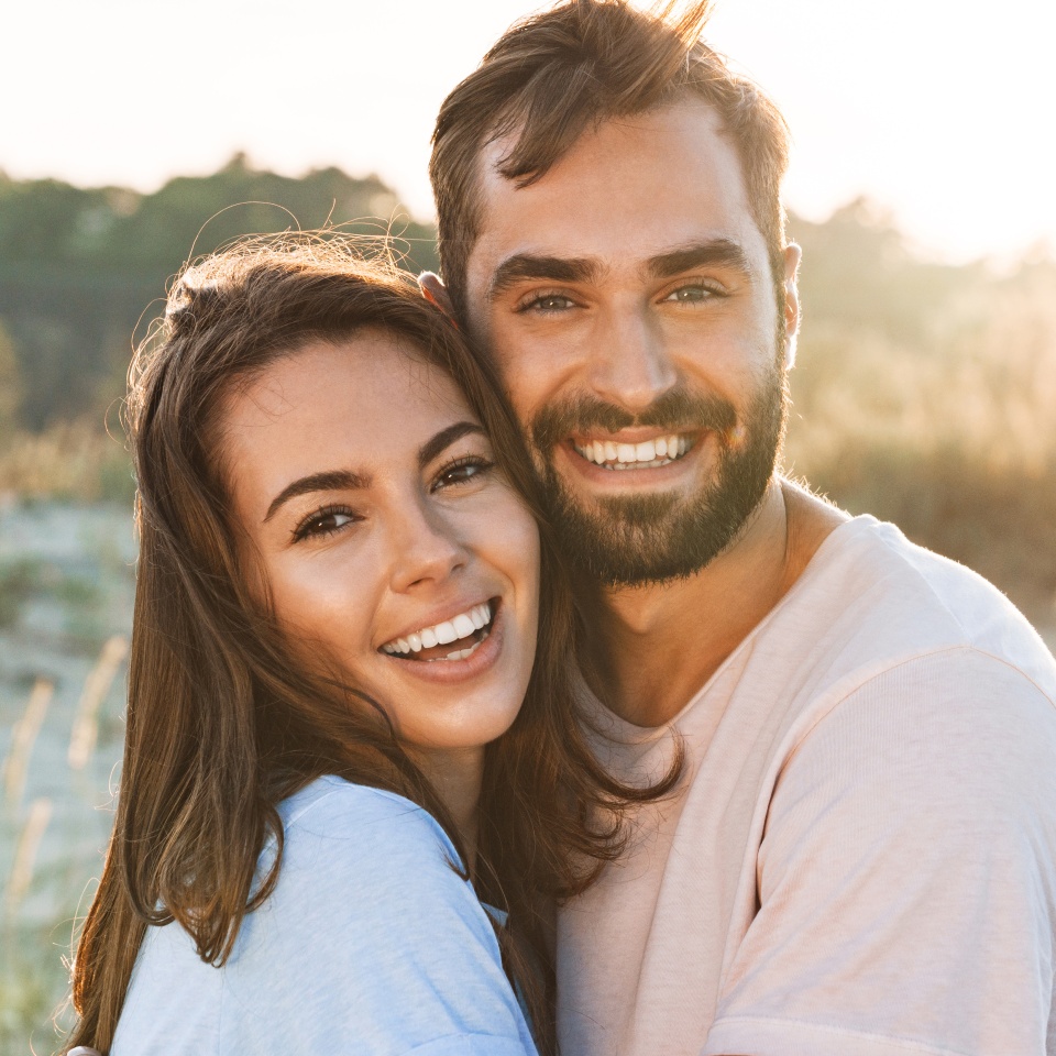 Beautiful young smiling couple spending time at the beach, hugging