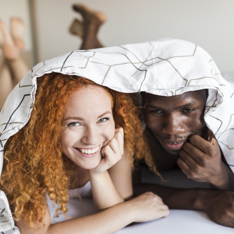 Front view of couple snuggling under the covers