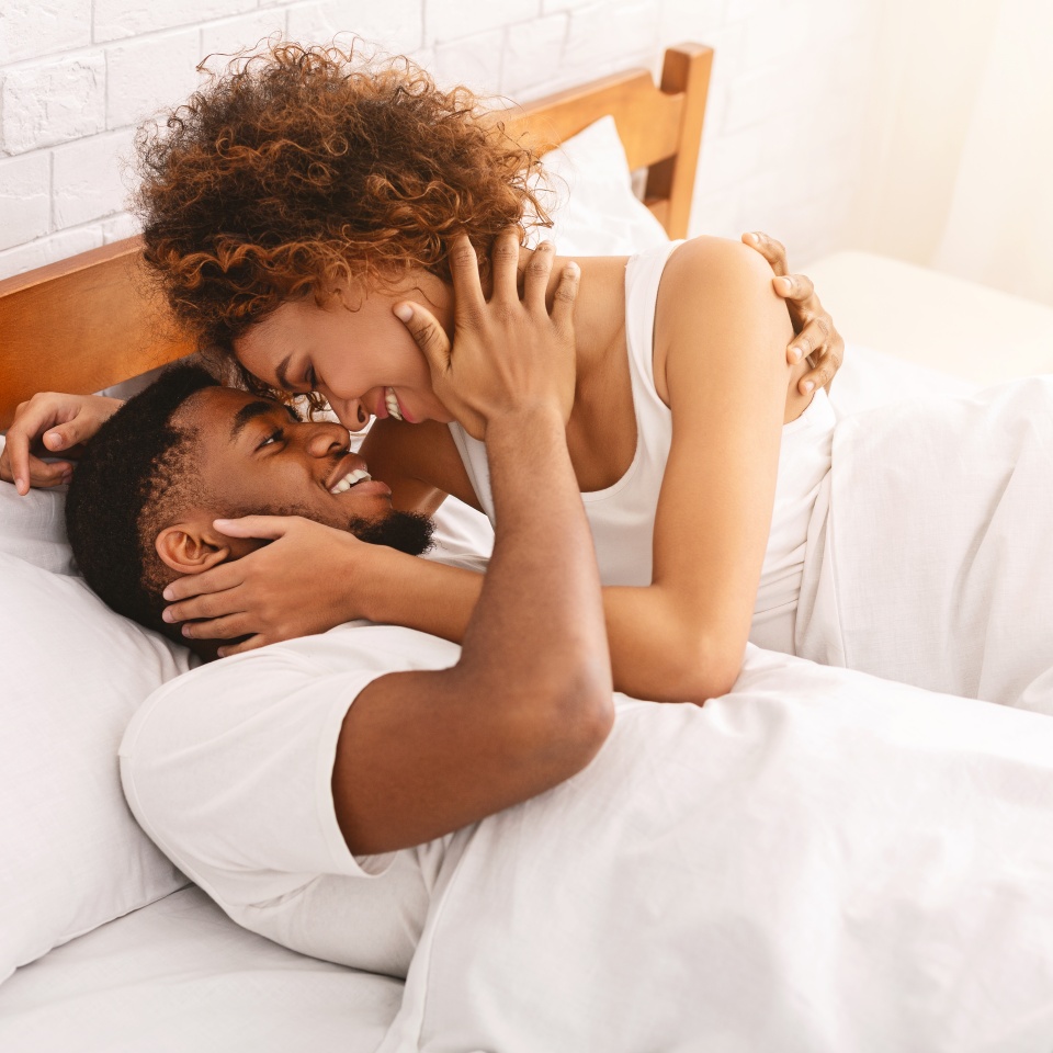 African couple of lovers relaxing in bed at home, enjoying each other, copy space