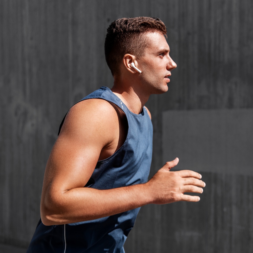 fitness, sport, training and lifestyle concept - young man in earphones running outdoors