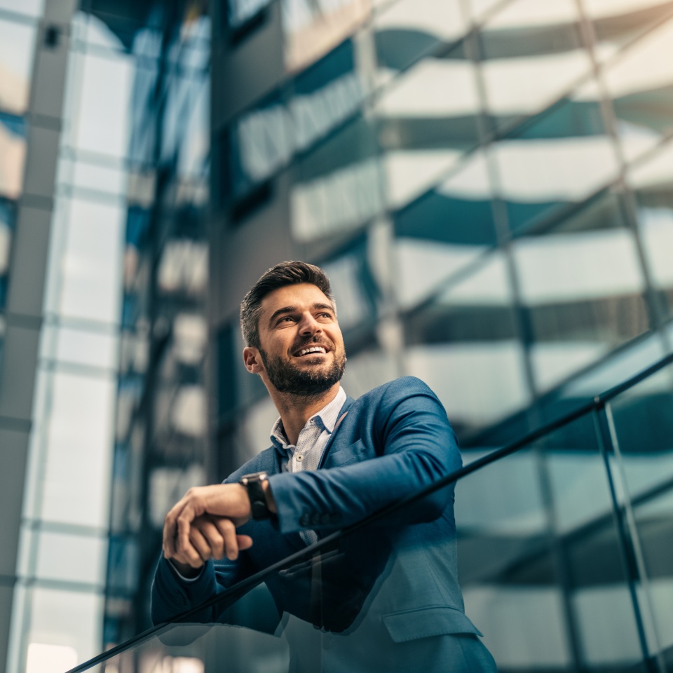 Handsome confident businessman portrait in front of modern buildings.