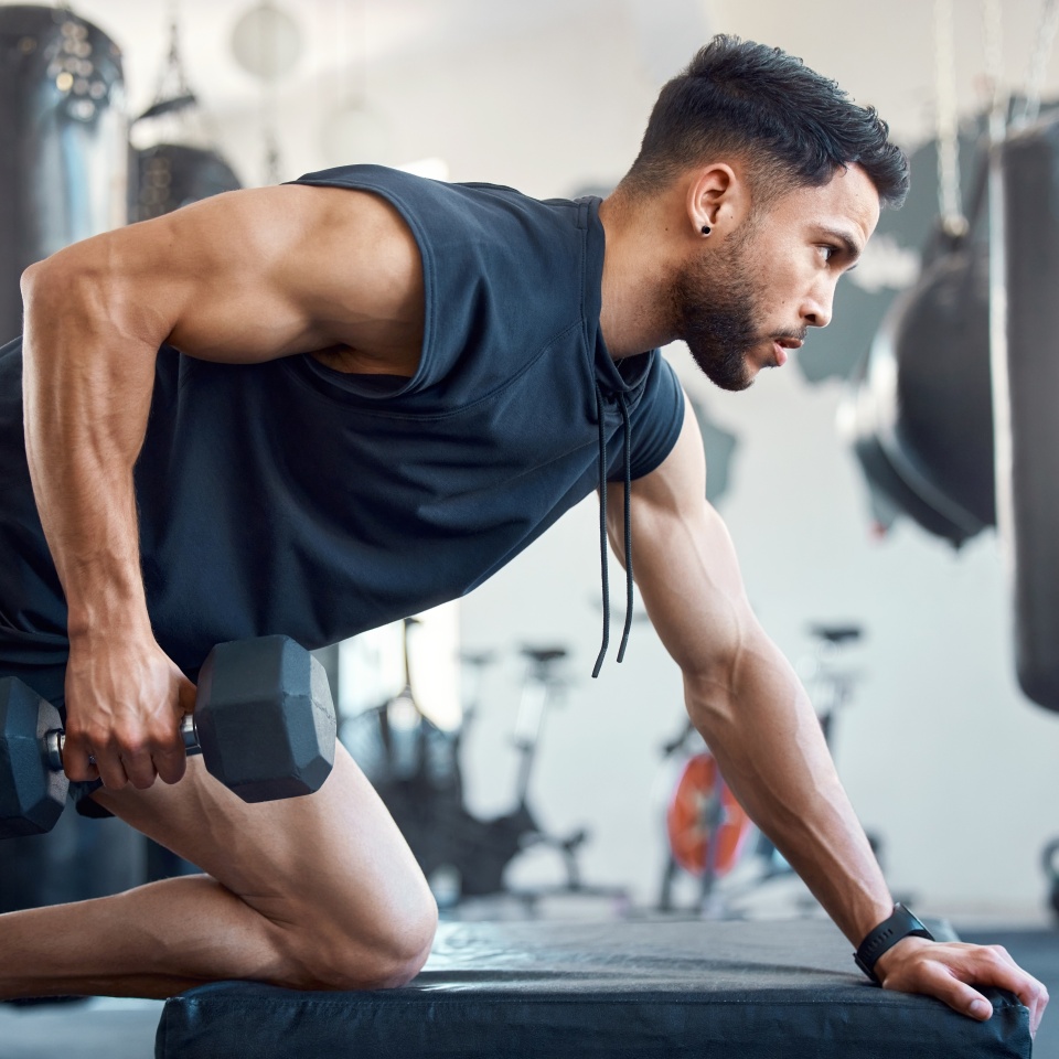 Shot of a sporty young man exercising with a dumbbell in a gym.