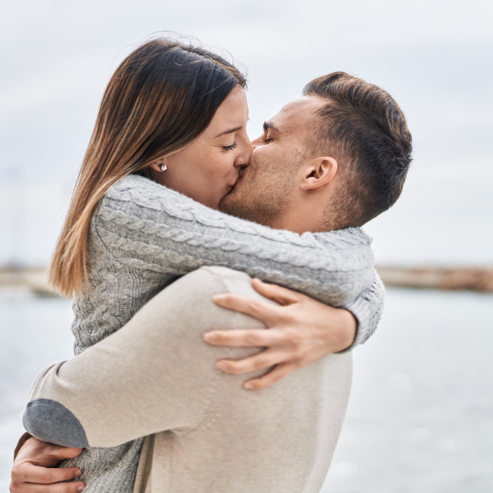 Man and woman couple hugging each other kissing at seaside