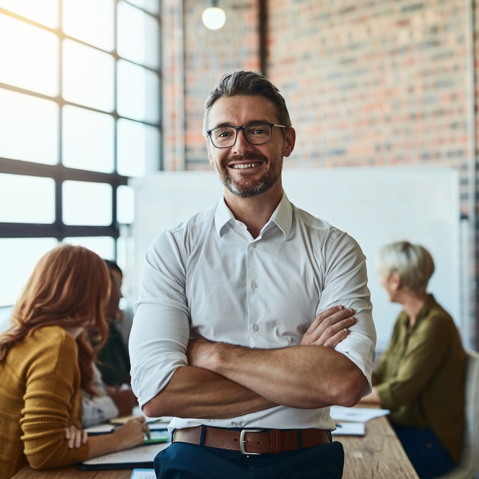 Cropped shot of a businessman standing in the office with his arms folded looking confident and smiling at the camera.