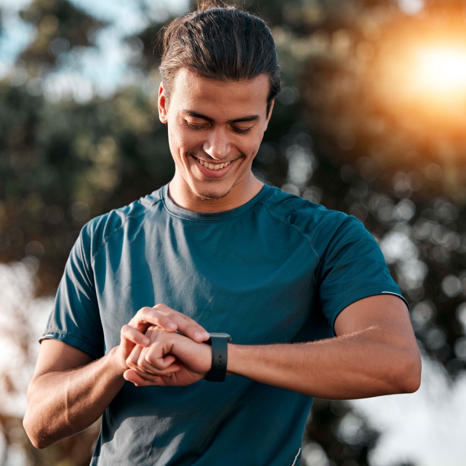 Smart watch, man and fitness at park for exercise workout, training and happy goals. Stopwatch, sports person and runner check time, heart rate or monitor healthy body progress, data app and wellness.