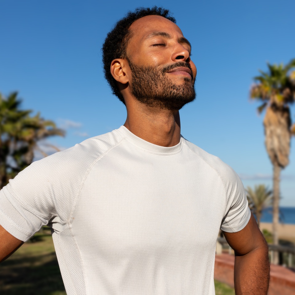 African American man breathing deeply in nature. Black man in sports clothing feeling good after exercising. Relaxation and sport concepts.