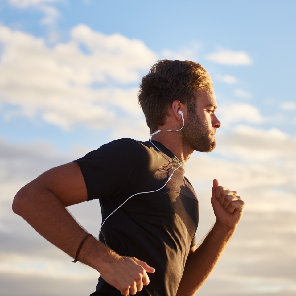 Young man jogging while listening to music on his earphones on the beach
